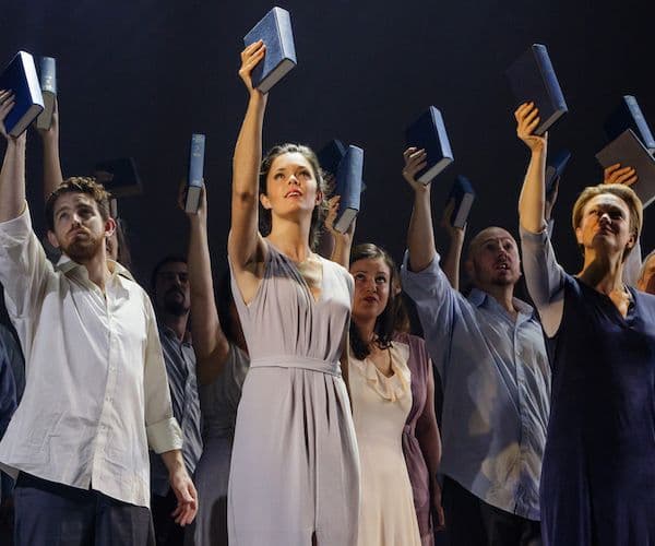Cast of Theodora on stage with each performer holding a book above their head