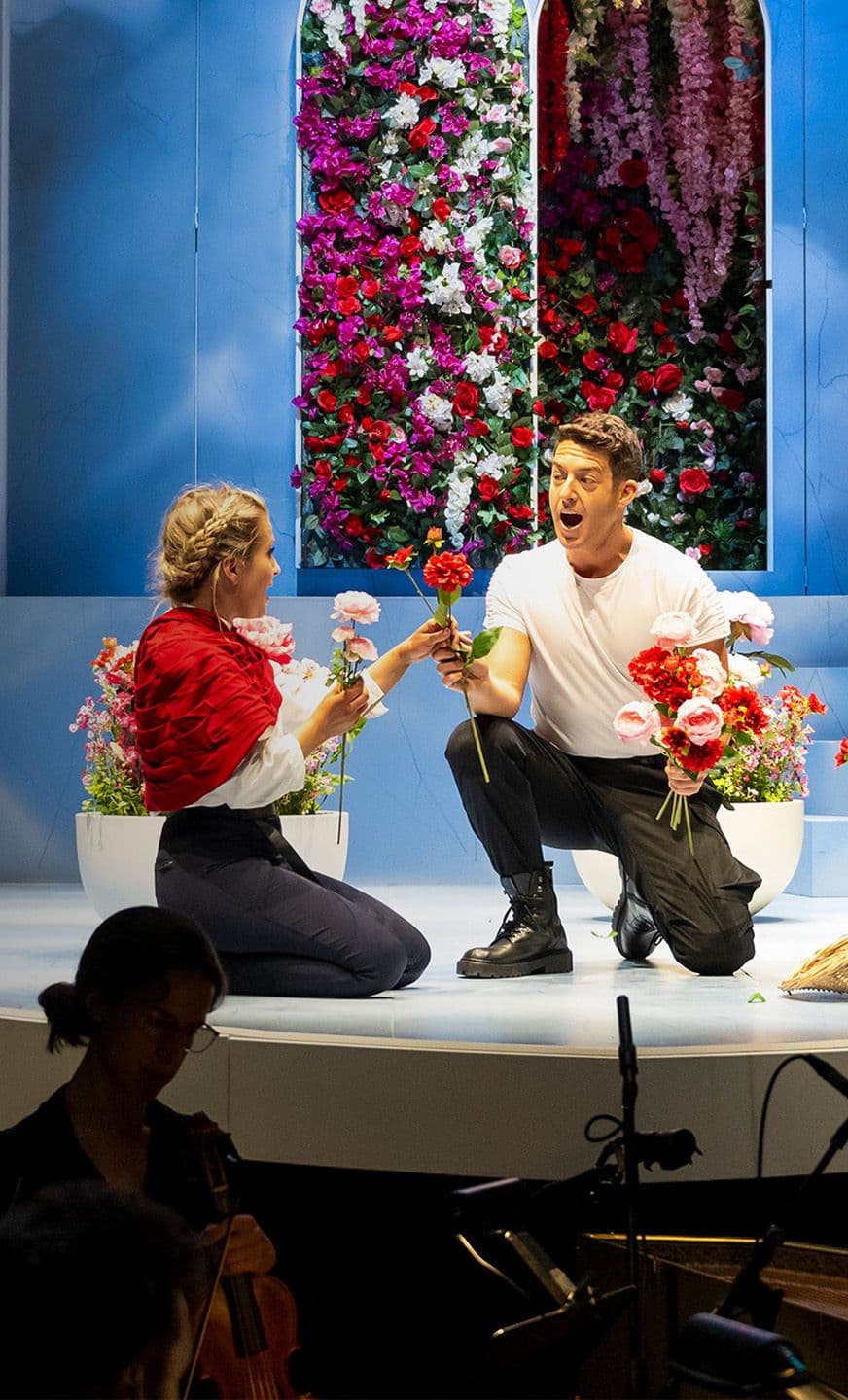 Tenor jake arditti as Rinaldo hands a flower to soprano Alexandro Oomens as Almiren