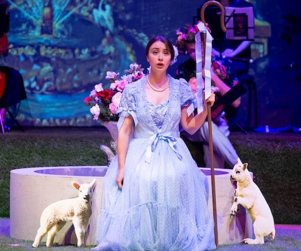 A soprano performing on stage wearing a lilac gown, in the middle of two lambs, for Pinchgut Opera's Pleasures of versailles