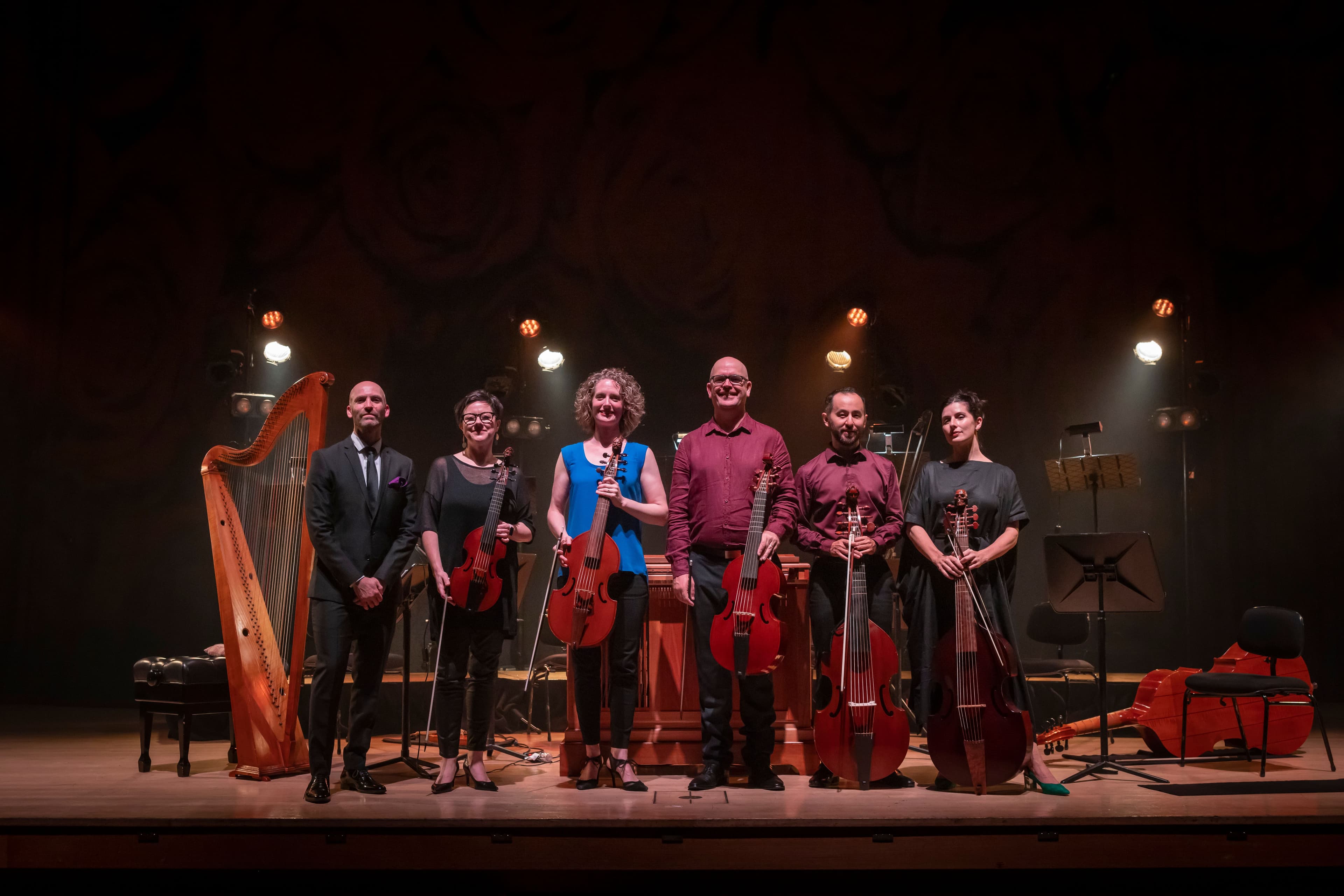 Six members of the Orchestra of the Antipodes stand in a line with their instruments after their performance of Membra Jesu Nostri
