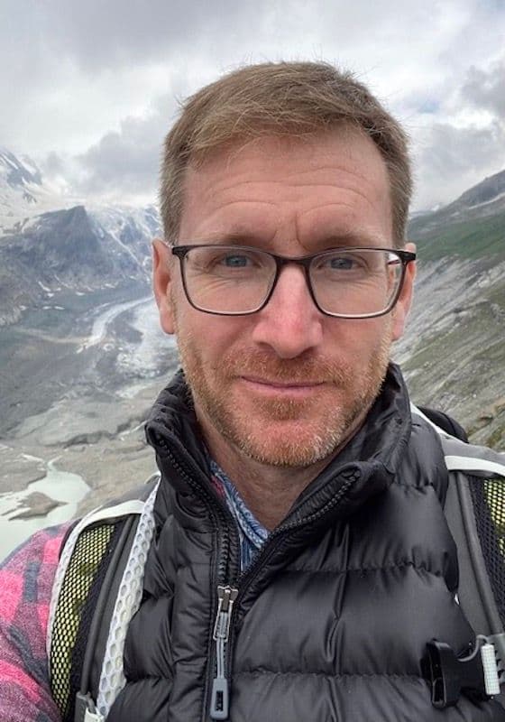 Headshot of Adam Grubner, with glasses and short dark blonde hair