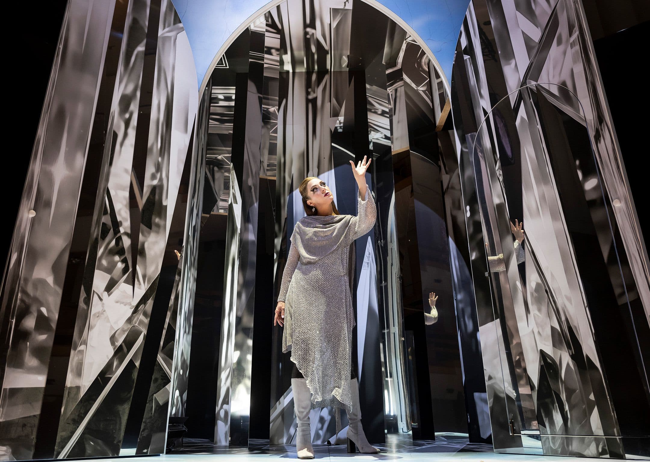 Soprano, Emma Pearson performs in Handel’s Rinalo in a silver dress next to a set piece that resembles shards of mirrors