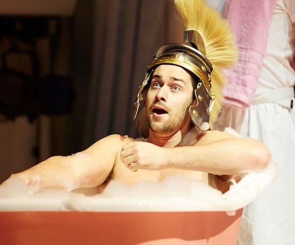 David Hansen performing onstage for Pinchgut Opera, wearing a knights helmet and sitting in a bathtub.
