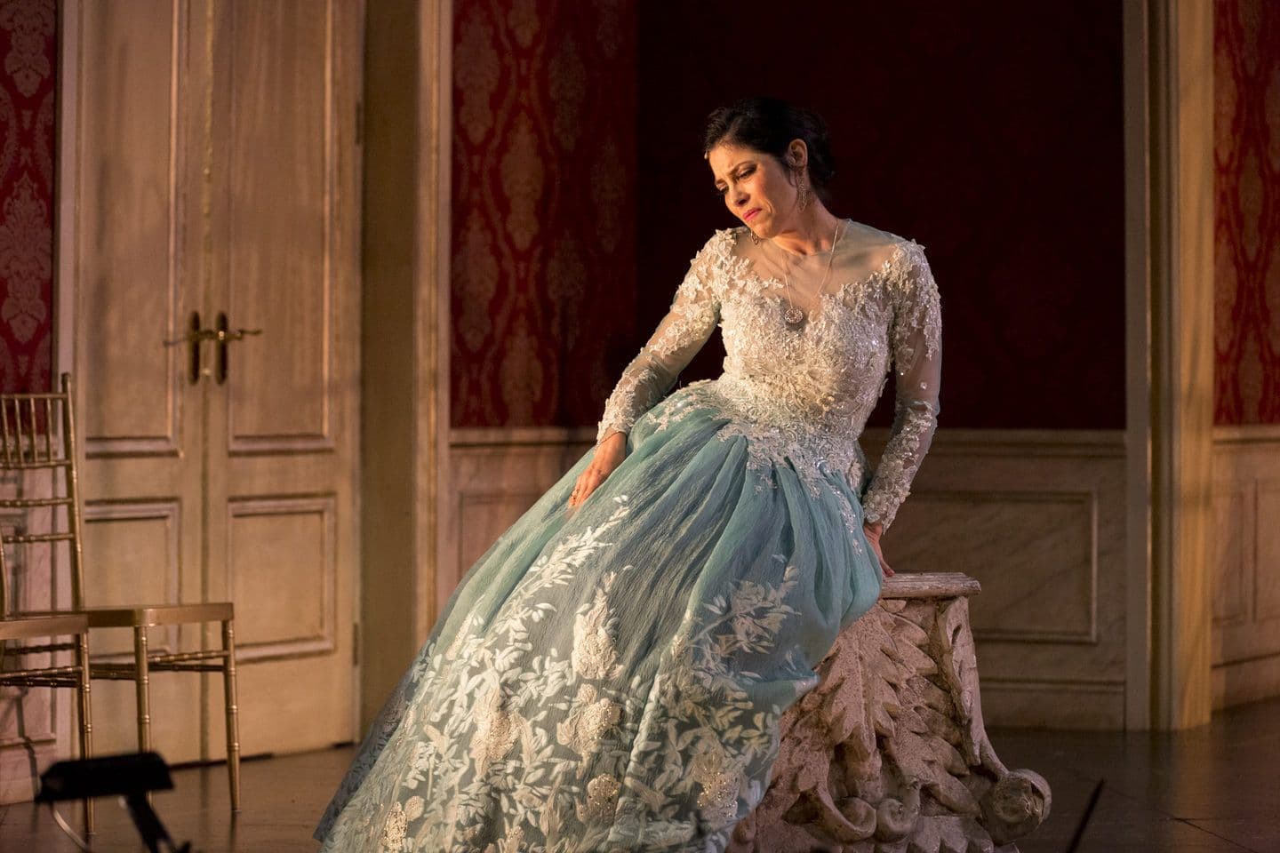 Soprano Vivica Genaux dressed in a dress with white a lacy top and pale blue skirt in a scene from Artaserse